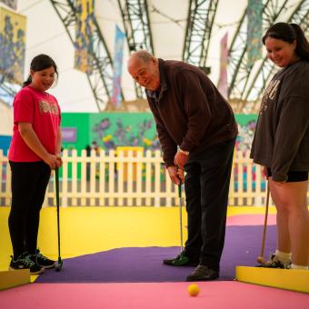 Grandfather and grand daughters playing crazy golf